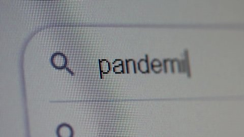 Typing Pandemic into Search Bar on Computer Monitor. Close Up.