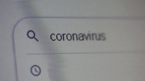 Typing Coronavirus into Search Bar on Computer Monitor. Close Up.