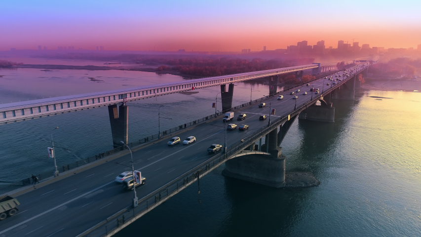 Aerial view of sunset in a big city on the river. The movement of cars on the bridge. Marvelous view. Fog over the river Royalty-Free Stock Footage #1054499615