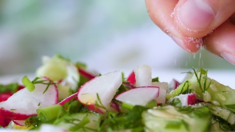Chef Sprinkles White Salt Vegetable Fresh Salad Food Healthy Meal Mediterranean Kitchen Vegetarian Diet. Slow Motion. Closeup Freshness Salad. Close up Healthy Colorful Food Onion Cucumber Radishes.