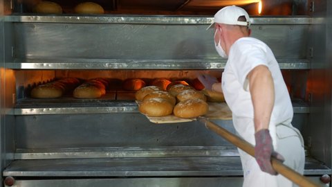 Chef removes freshly baked bakery products from the oven. Baked bread is removed from the oven in a bakery.
