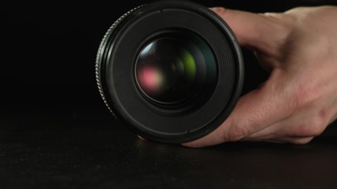 Male hands opening and closing the aperture of the removed lens.