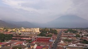 Antigua Guatemala aerial drone video of colonial city at sunset with volcano in background