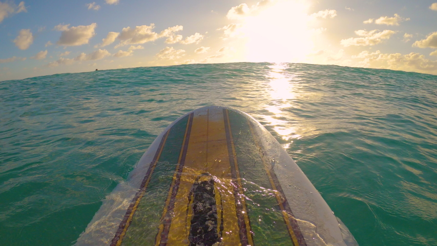 POV, LENS FLARE: Sitting in line up on a vintage longboard, observing the golden sunset during a fun surfing trip in the Caribbean. Surfer sits on surfboard and waits for waves on a sunny evening. | Shutterstock HD Video #1054510781