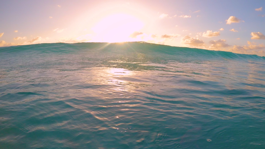 SLOW MOTION, CLOSE UP: Small tube wave sweeps over the camera on a sunny summer evening in the Caribbean. Idyllic shot of a turquoise barrel wave rolling over the camera filming the golden sunset. | Shutterstock HD Video #1054510796