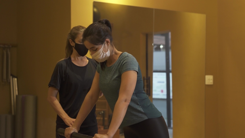 Pilates. Classes with a trainer wearing face mask agains corona virus at the gym Pilates on a special simulator. Loosen restrictions. Reopen Royalty-Free Stock Footage #1054510982