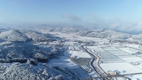 Drone shot of rural farmland agricultural scene in winter, snowy trees and land, South Korea