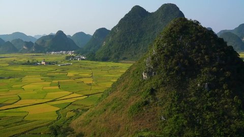 Aerial view, rice fields and farmlands surrounded by mountains, rural scene in Guangxi of China, karst landform, panning shot