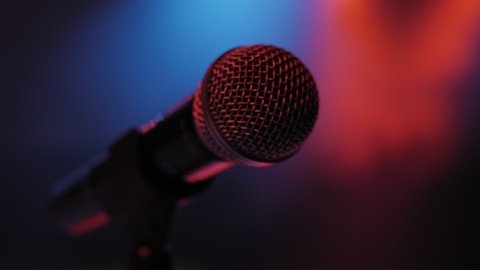 Concert microphone on the stage in the dark with the light red and blue bright lights. Microphone in a smoke on a dark background. Music instrument concept.
