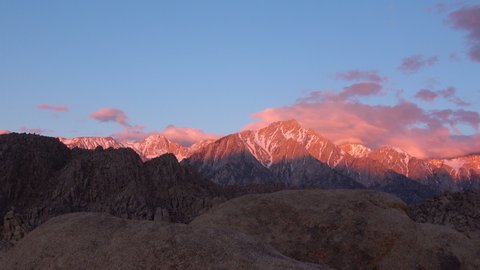 Pan shot of morning sun illuminating alpine peaks of Sierra Nevada mountains in California