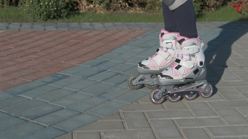 Rollerblading with music. A pretty child start to skate with her headphones on the paving street in the part.