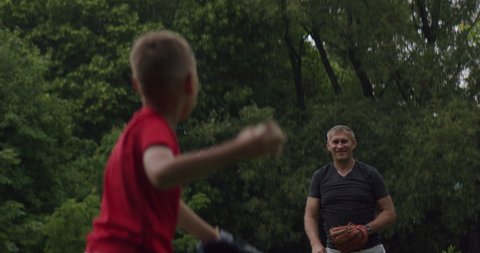 MED Father and son playing baseball catch in the park on a rainy day. Family time spent together. Shot with 2x Anamorphic lens