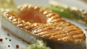 Meal with salmon fish steak and vegetable. Bottle of Olive oil pouring on salmon fish. Healthy food. Main course Close up. Slow motion video footage. Slowmo. Slow-mo