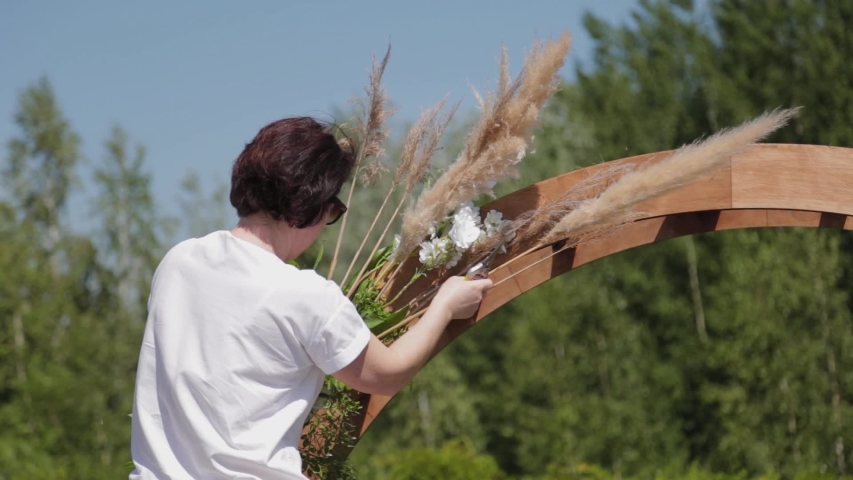 Wedding decorator decorates the place of registration of marriage with fresh flowers.