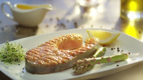 Meal with salmon  steak and vegetable. Bottle of Olive oil pouring on salmon fish. Healthy food. Main course Close up. Slow motion video footage. Slowmo. Slow-mo