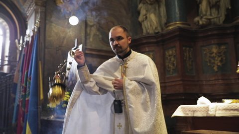 Saints Peter and Paul Garrison Church Lviv, Ukraine - February 29, 2020. Greek Catholic rite. Priest in ritual action using incense with frankincense producing the smoke in the church.