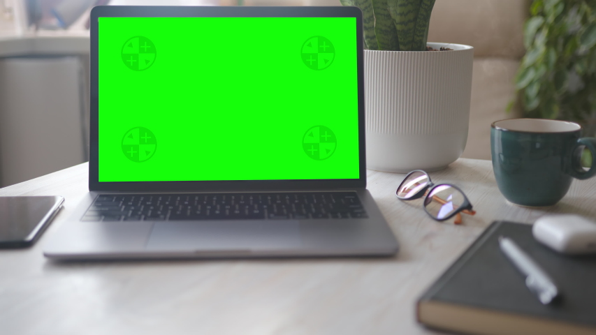 Mock-up Laptop Computer with Chroma Key Green Screen Set on Working Space in Home Office. A Cup of Hot Coffee near the Computer. Concept of Working from Home. Zoom in Shot. Royalty-Free Stock Footage #1054538723