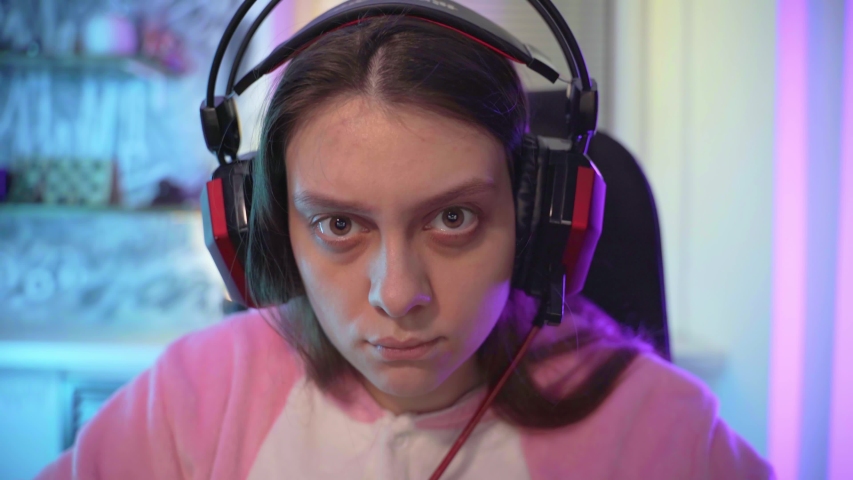 A young girl gamer emotionally plays a computer game.