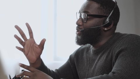 African American male, call center agent in headset consult business client online using laptop \ black man in headphones leads an online webinar