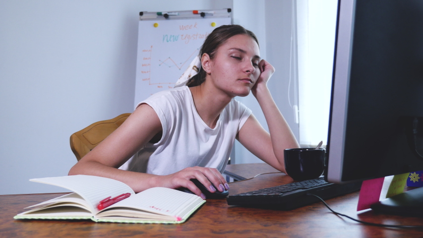 Young tired woman in sitting at the laptop computer while working in the office, then almost falling asleep and waking up. Indoor. | Shutterstock HD Video #1054550606