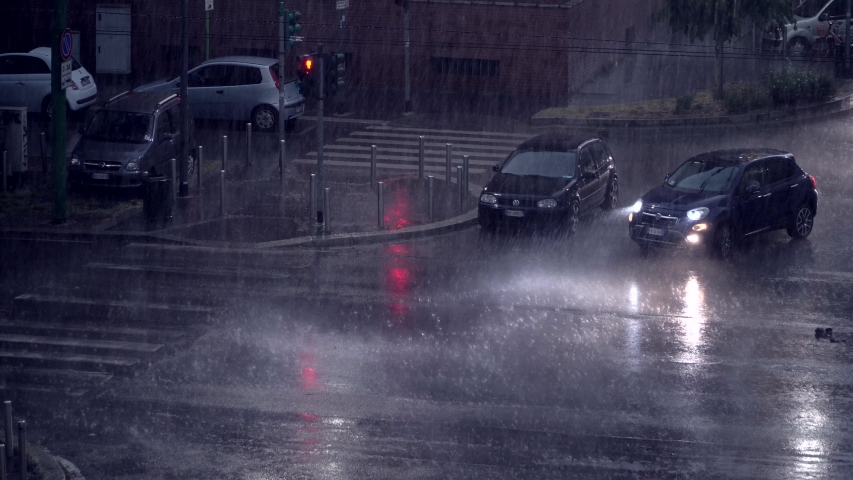 Milan, Italy. Night city in rainy weather. Cars passing on the wet asphalt of city streets. Traffic lights at night. Reflection in puddles on the ground. Crossroads at night. food delivery bike. 