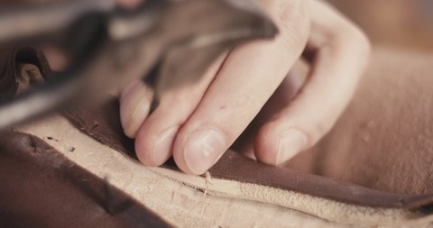 Traditional bespoke shoemaker nails leather upper on a wooden shoe last with lasting pliers unrecognizable macro close up