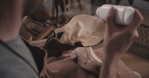 Traditional bespoke shoemaker apply powder on leather upper in his workshop unrecognizable over shoulder close up slow motion