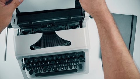 above view of person inserting sheet of paper into old typewriter