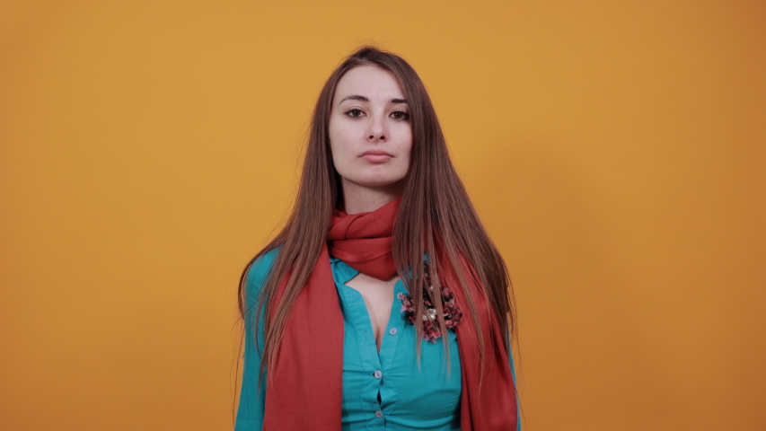 Pointing to head with fingers, great idea or thought, good memory, posing funny and crazy hand on temple, mood, cool. Young attractive woman with brown hair, eyes, blue shirt, yellow background
