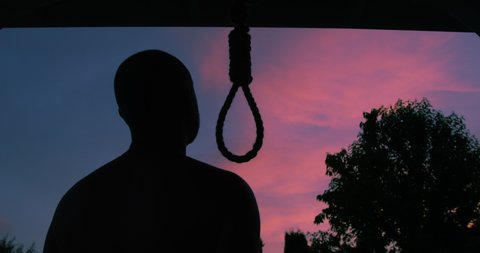 Man Trying to Commit Suicide by Hanging Himself on a Hangman Rope Changing his Mind and Leaving in Silhouette on a Sunset Sky Background a Concept New Life]