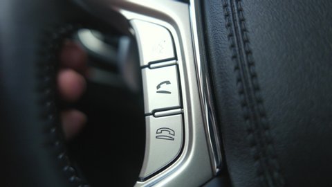 Using the Bluetooth buttons located on the steering wheel of a car to talk over the phone hands-free.