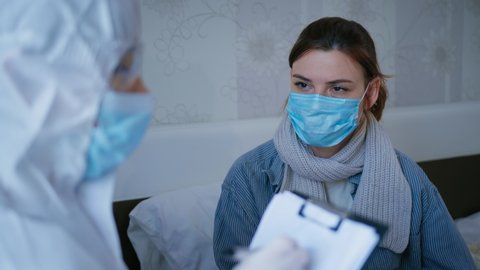 health care, unhealthy female patient in medical mask for protection against virus and disease consults doctor in protective suit, complains of ill health possibly due to coronavirus during doctor
