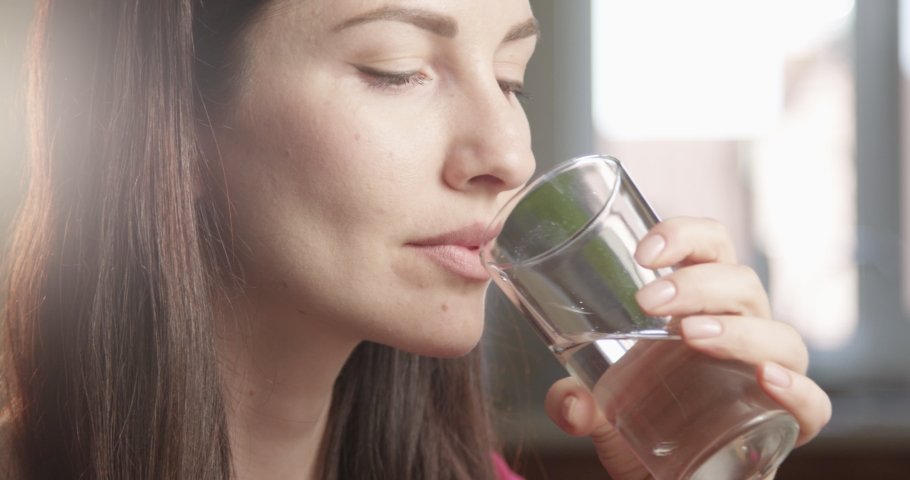 Thirsty Woman Drinking Water from a Glass Indoors with Sun Shining a Close up Shot on Red Camera Royalty-Free Stock Footage #1054561460