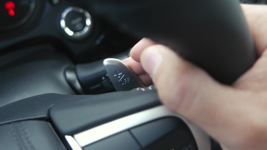 Closeup on a person sitting inside the vehicle and using Paddle Shifters to change gears while driving Royalty-Free Stock Footage #1054561589