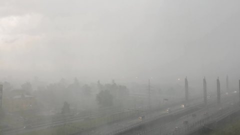 Heavy rain thunderstorm with wind gusts, hail in the city, poor visibility on the road.