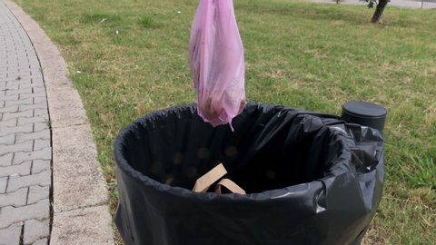 Slow motion: Man throws dog poop in the waste bin during a walk in nature