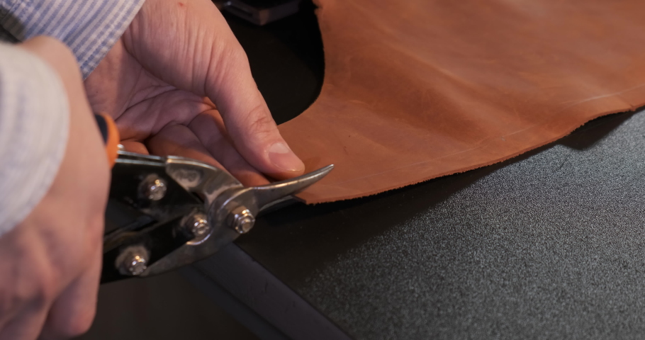 Man Using Scissors Cut Brown Leather Sheet, Leather Craftsman Creates Product with his Hands, Leather Making Process in Home Office. Small Business at Leather Industry. Production of Designer Clothes | Shutterstock HD Video #1054566926