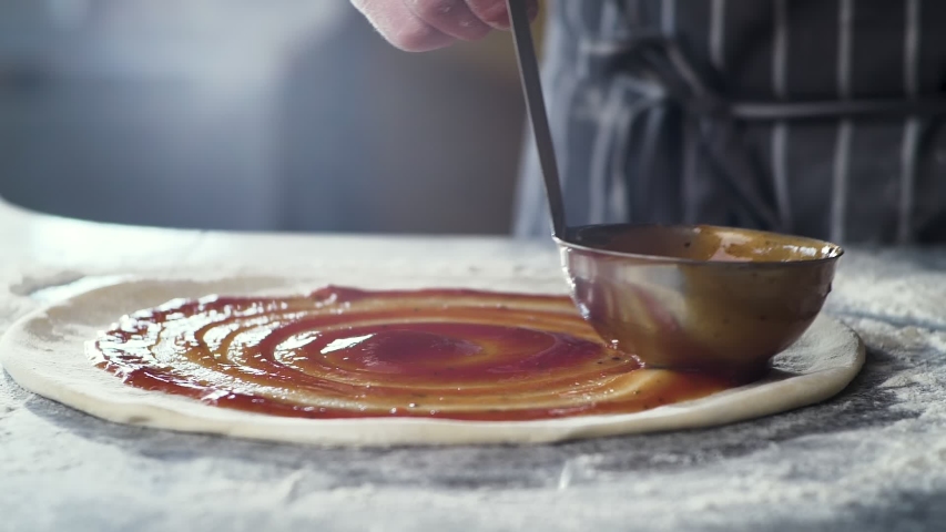Close Up of Chef is spreading Tomato Sauce on Pizza Dough with a Metal Ladle in Traditional Italian Pizza's Restaurant. Cooking traditional Sauce for Italian Pizza. Italian Food. Pizza's Making. | Shutterstock HD Video #1054570112