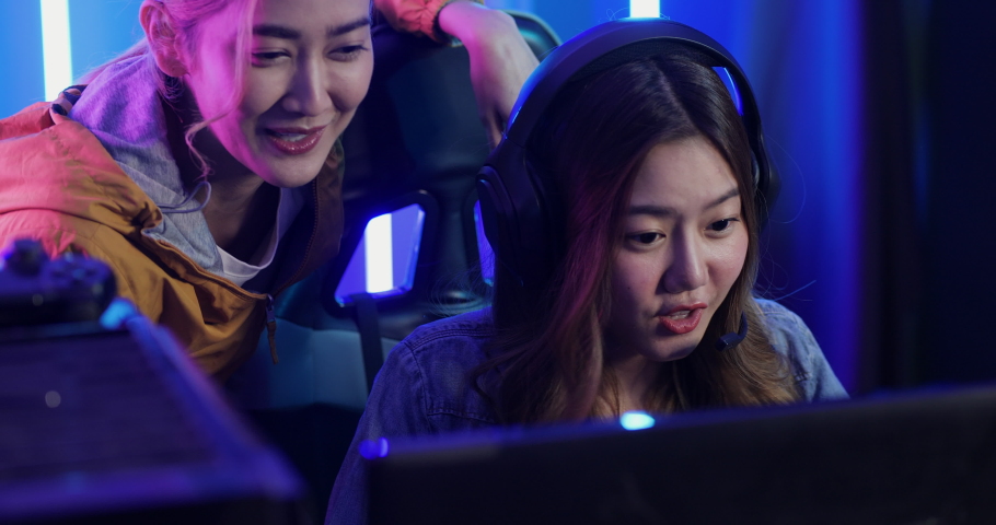 Young Asian team woman gamer having live stream and playing in Online Video Game. They playing and winning in video games on a computer.