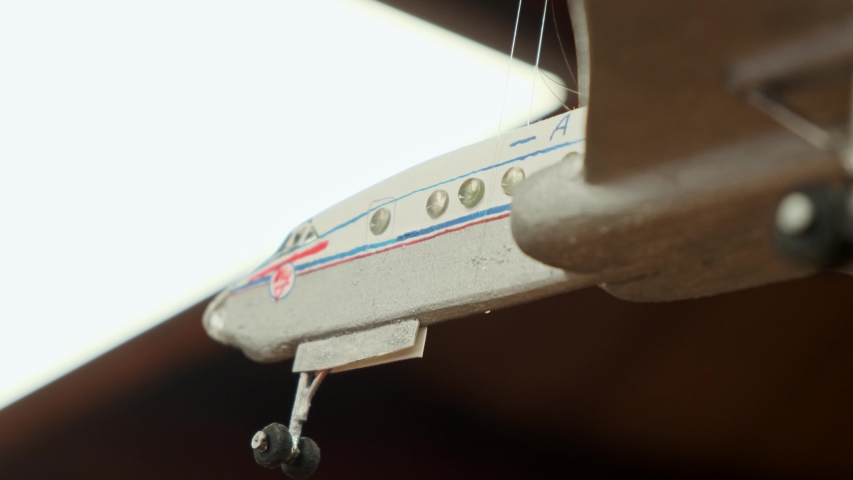 beautiful painted wooden model of vintage passenger Ilyushin jetliner hangs on brown threads slow motion extreme closeup