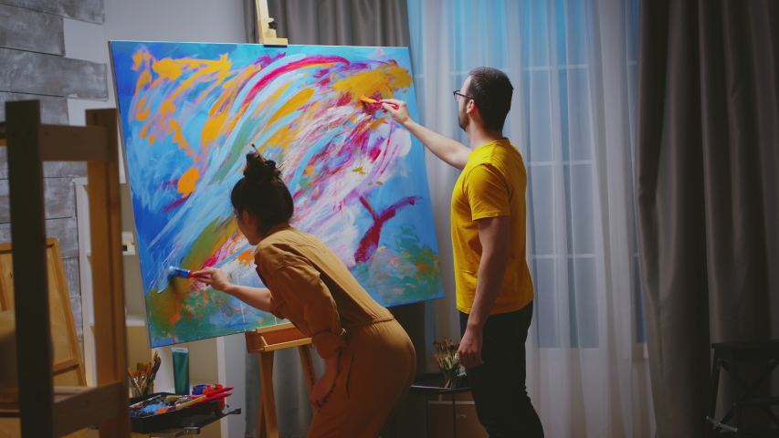 Man and woman painters working together in art studio on large canvas. Modern artwork paint on canvas, creative, contemporary and successful fine art artist drawing masterpiece Royalty-Free Stock Footage #1054578041