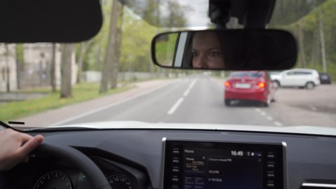 Reflection of a woman in a rearview mirror of car brunette woman driving automobile, woman eyes in rear view mirror closeup.