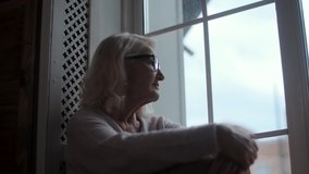 Thoughtful elderly old woman, looking towards the window, being alone in the evening, thinks about a serious problem. A woman misses her daughter and grandchildren, remaining in isolation. - Powered by Shutterstock - Get 15% off with code: PIKWIZARD15