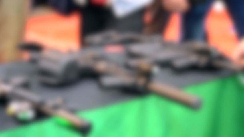 Blurred background. Several large-caliber weapons on the table