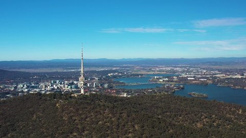 Aerial flyby of Telstra Tower in Canberra, the capital of Australia, showing a panoramic view of Lake Burley Griffin and surrounding landmarks and countryside       