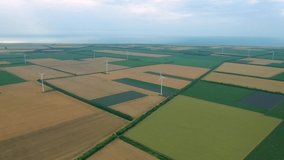 Aerial fly above wind turbines across summer agricultural field. Clean and renewable wind power farm in motion. Green energy, sustainable alternative electricity, no pollution environment.