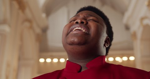 Close up view of emotional afro american pastor singing worship. Portrait of young male gospel singer in church. Concept of music and religion.