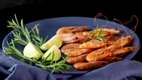 Beautiful boiled large shrimp in ceramic plate with parsley and lime. Fresh seafood ingredient - shrimp tails ready for cooking. Boiled prawns. Slow move 4k video