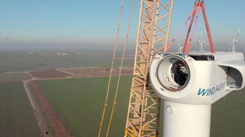 Building process of wind energy power tower mill, under construction. Installation of gondola, inside gondola. Green, clean, renewable energy. Aerial footage.