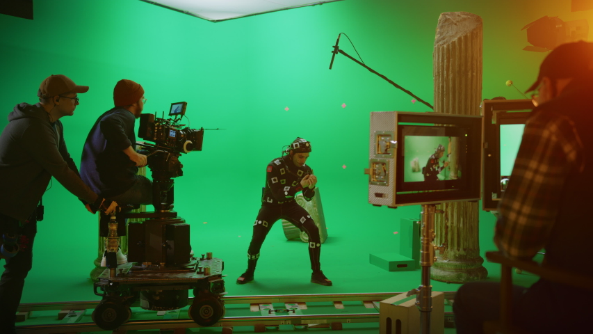 Director Commands Camera Operator to Start shooting Green Screen CGI Scene with Actor Wearing Motion Tracking Suit and Head Rig. Big Film Studio Professional Crew Shooting Blockbuster Movie